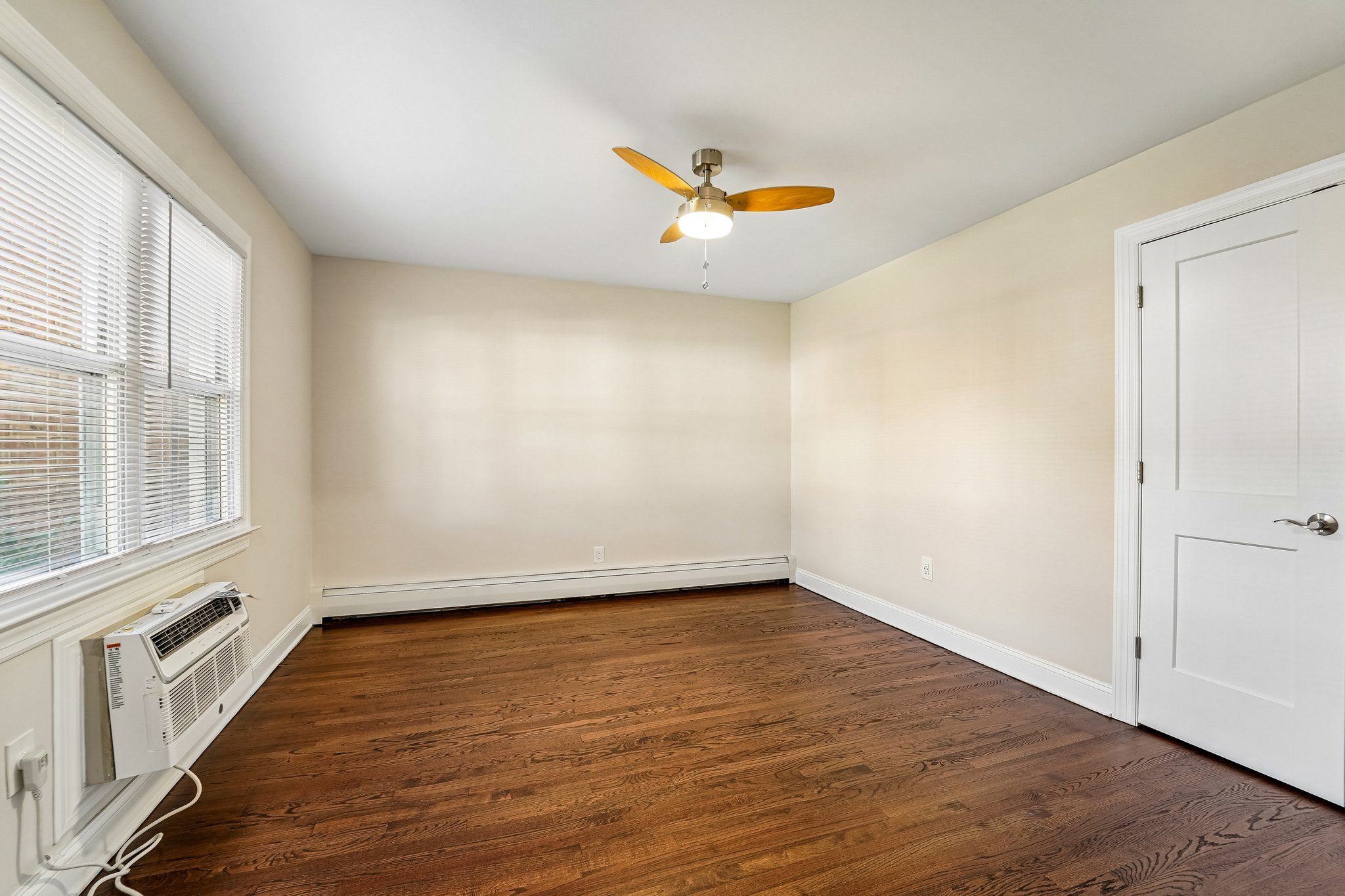 A room with a ceiling fan and a window with blinds.